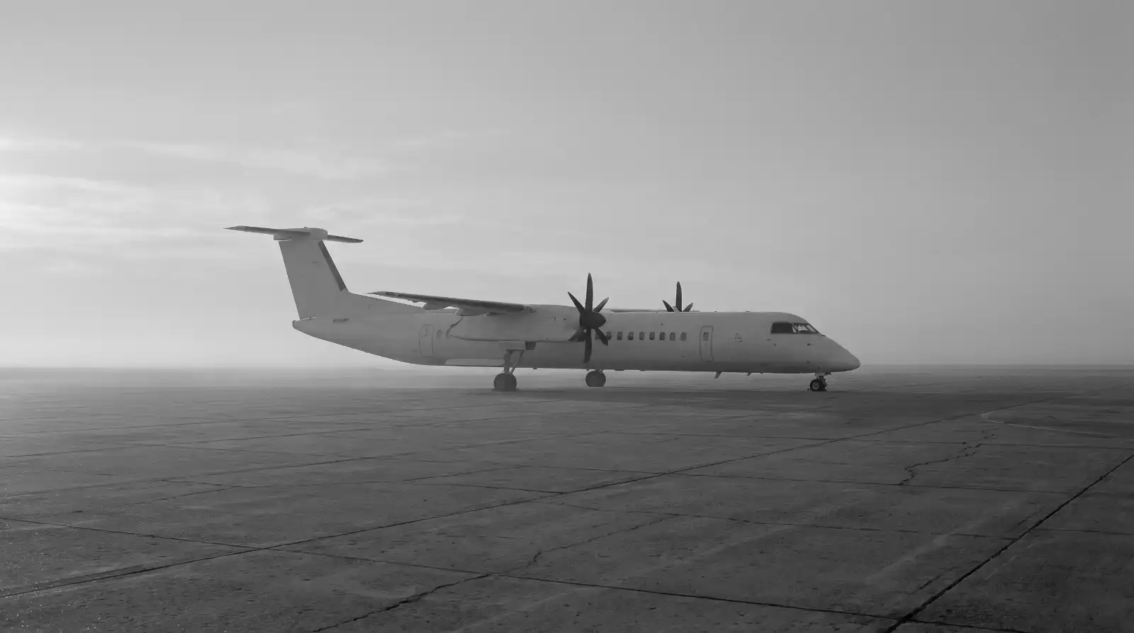 Twin-turboprop aircraft on an empty apron at dawn